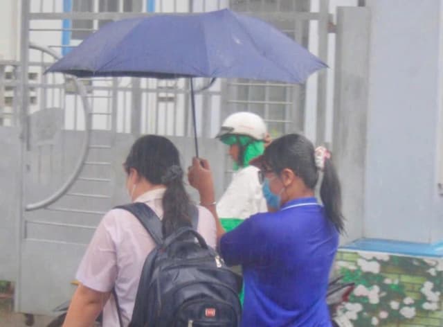 Tình nguyện viên che chắn cho thí sinh trong cơn mưa tầm tã
